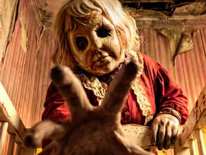 A terrifying-looking doll with a disfigured face reaches towards the camera. It's a still from the horror film 'Dolly' - and SWITCH is giving you the chance to win copies on Blu-ray!