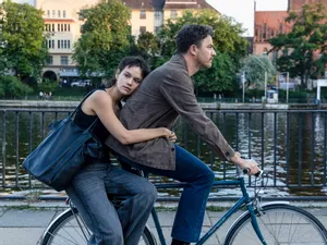 A man and a woman on a bicycle riding alongside a river. A still from the movie 'Wunderschöner', which is showing at the 2026 Europa! Europa Film Festival - and SWITCH is giving you the chance to win double passes to the festival!